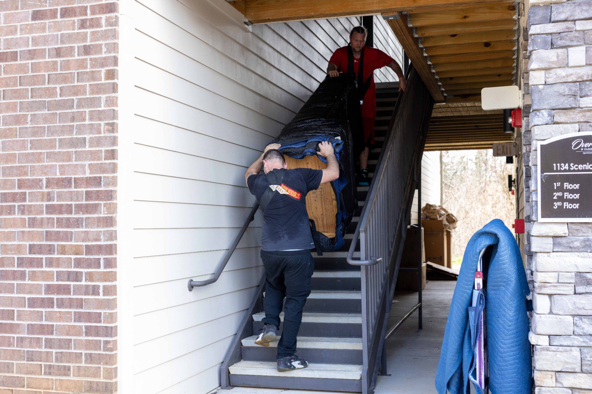 Midas Touch Moving crew carrying padded furniture up apartment stairs during a move in Knoxville Tennessee