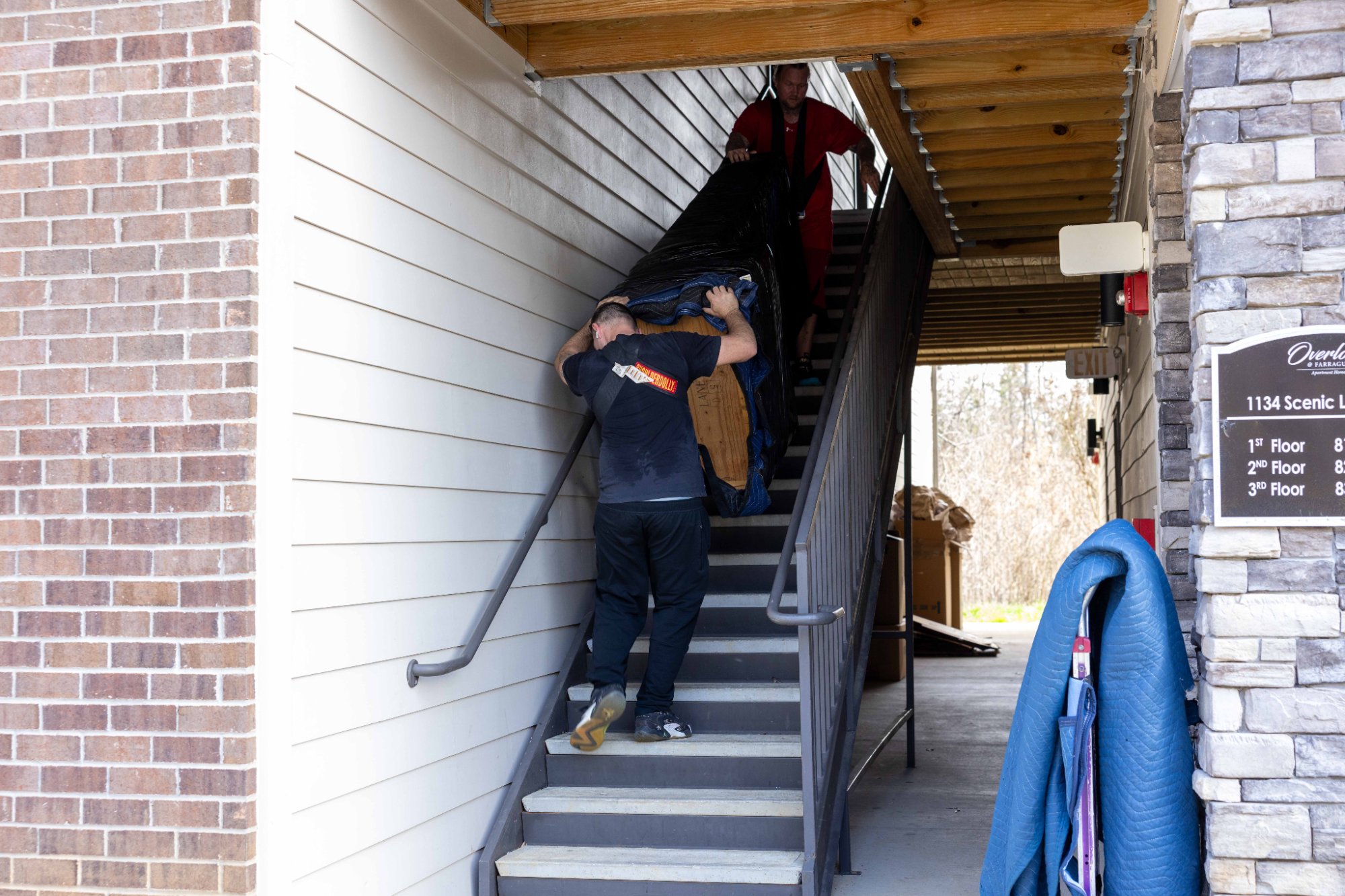 Two Midas Touch movers carrying a couch up apartment stairs during a move in Sevierville Tennessee